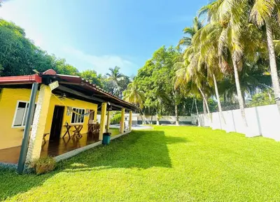 a yellow house with a yard with palm trees at Rancho El Ancla Surf City Wi-Fi AC Pool in La Libertad