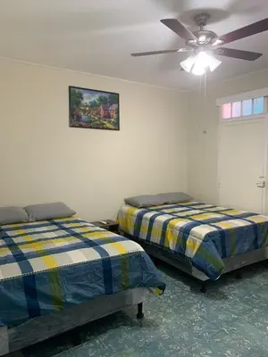 two beds in a room with a ceiling fan at Hostal primaveras nest centro santa ana hab2 in Santa Ana
