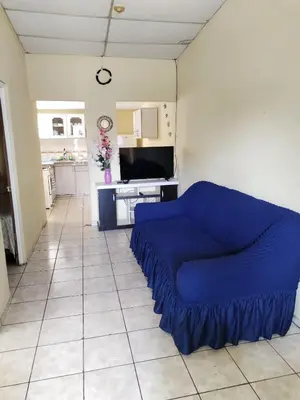a blue couch in a living room with a kitchen at bonita casa pequeña in Santa Ana