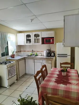 a kitchen with white cabinets and a table with a table cloth at bonita casa pequeña in Santa Ana