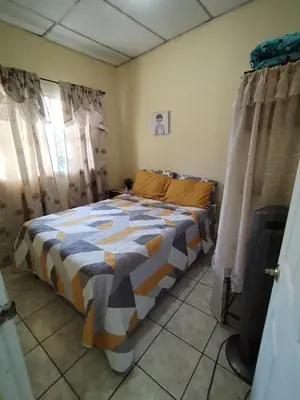 a bedroom with a bed in a room with curtains at bonita casa pequeña in Santa Ana
