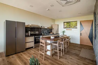 a kitchen with a wooden table and a refrigerator at Wave House in El Zonte