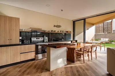 an open kitchen with a wooden table and chairs at Wave House in El Zonte