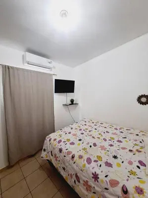 a bedroom with a bed with a flowered comforter at casa familiar, HOME sweet HOME san Miguel