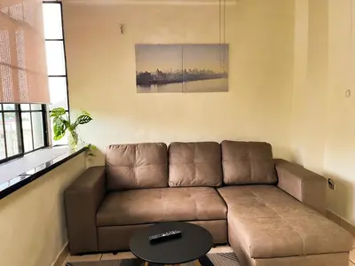 a living room with a brown couch and a table at Apartamento dos habitaciones baños completos WiFi y AC todo el apto, parqueo interno,San Salvador, Colonia escalón in San Salvador