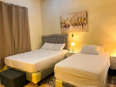 a bedroom with two beds and a painting on the wall at Apartamento dos habitaciones baños completos WiFi y AC todo el apto, parqueo interno,San Salvador, Colonia escalón in San Salvador