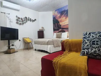 a bedroom with a bed and a couch and a tv at Lofts #9 & #6 Surf EcoVilla Playa El Sunzal in El Sunzal
