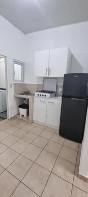 a kitchen with a black refrigerator and white cabinets at Residencia en Megápolis, San Miguel in San Miguel