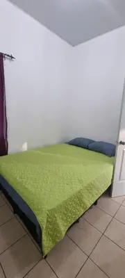 a bed with a green comforter in a room at Residencia en Megápolis, San Miguel in San Miguel