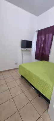 a bedroom with a green bed and a tv on the wall at Residencia en Megápolis, San Miguel in San Miguel