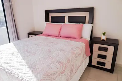 a bedroom with a bed with pink pillows and a nightstand at Beautiful Modern Home in Res San Andres in San Miguel