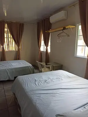 a bedroom with two beds and a chair and windows at Las Brisas Casa frente al mar Costa del Sol in El Zapote