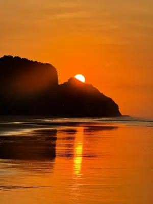 a sunset on the beach with the sun setting behind a mountain at Sihua Escape in Teotepeque