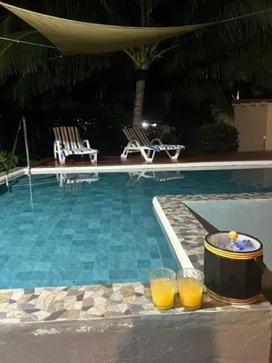 two glasses of orange juice sitting next to a swimming pool at Sihua Escape in Teotepeque