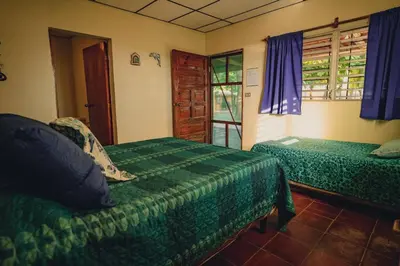 a bedroom with two beds and a window with purple curtains at Sihua Escape in Teotepeque