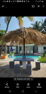 a large straw umbrella sitting in front of a pool at Beach house playa san diego in La Libertad