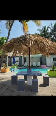 a large straw umbrella sitting next to a swimming pool at Beach house playa san diego in La Libertad
