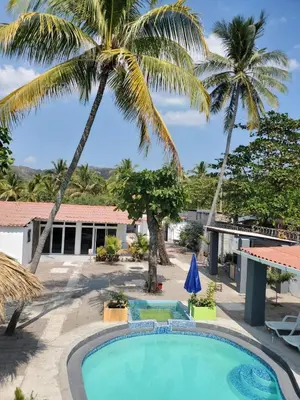 a pool with palm trees and a building at Beach house in la libertad in La Libertad
