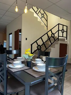 a dining room table with chairs and a staircase at Bambú Family House, AC, WiFi, near Metrocentro Mall in Santa Ana