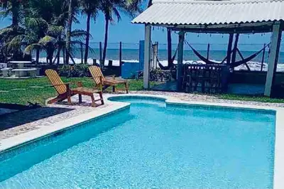 a swimming pool with two chairs and a gazebo at Casa De Playa Atlantis in San Luis