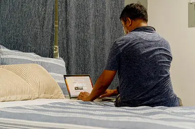 a man sitting on a bed using a laptop computer at Hotel Five Stars sv in Berlín