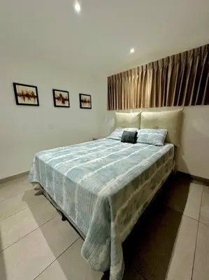 a bedroom with a bed with a blue comforter at Cool Spot By Rooftop Masferrer in San Salvador