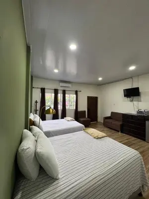 a bedroom with two beds and a living room at Emmitas room in Juayúa