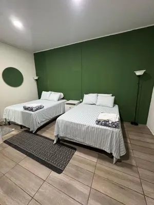 a room with two beds and a green wall at Emmitas room in La Unión