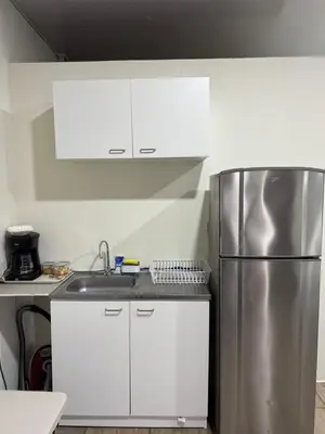 a kitchen with white cabinets and a stainless steel refrigerator at Emmitas room in La Unión