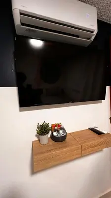a tv on a wall with a wooden shelf with a plant at Quaranta Lofts in Antiguo Cuscatlán