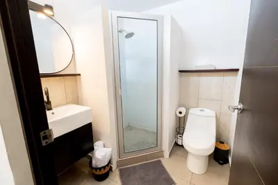 a bathroom with a toilet and a glass shower at Quaranta Lofts in Antiguo Cuscatlán