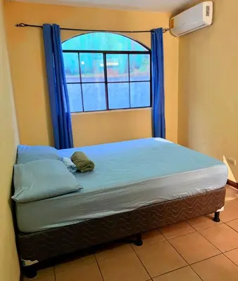 a bed in a room with a window with blue curtains at casa en la Cima in San Salvador