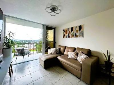 a living room with a couch and a balcony at Amazing City Views, with Queen Bed and Pool in San Salvador