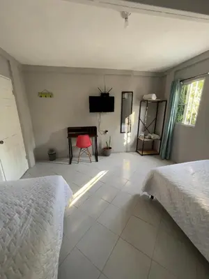 a bedroom with two beds and a desk and a television at Habitación cerca del aeropuerto #3 in La Paz
