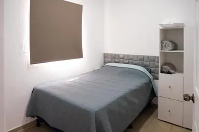 a small bedroom with a bed with a blue blanket at La Petite Santa Ana in Santa Ana