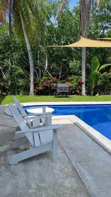 a bench and an umbrella next to a pool at Casa con Piscina y Rancho, cerca de Estero y Playa in El Zapote