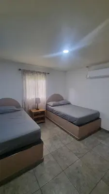 a bedroom with two beds and a table with a lamp at Casa con Piscina y Rancho, cerca de Estero y Playa in El Zapote
