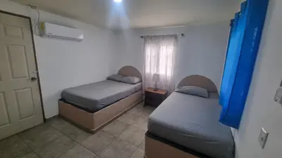 two beds in a room with a door and a window at Casa con Piscina y Rancho, cerca de Estero y Playa in El Zapote