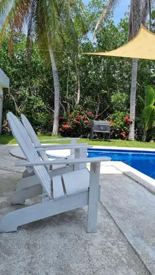 a bench with a umbrella next to a pool at Casa con Piscina y Rancho, cerca de Estero y Playa in El Zapote