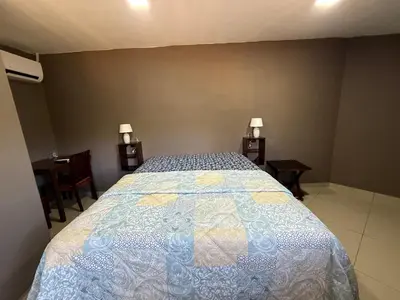 a bedroom with a bed and two tables and two lamps at Mini Room El Mangal B&B in Suchitoto