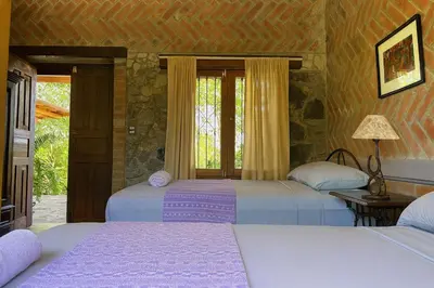 a bedroom with two beds and a window at Los Cuatro Olivos Hotel Boutique in Juayúa