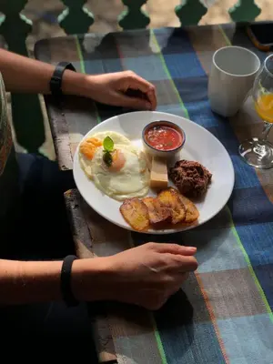 a person sitting at a table with a plate of food at Los Cuatro Olivos Hotel Boutique in Juayúa