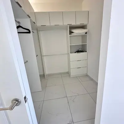 a walk in closet with white cabinets and a tiled floor at Beauty delux home in San Miguel