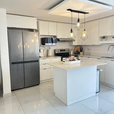 a kitchen with white cabinets and a stainless steel refrigerator at Beauty delux home in San Miguel