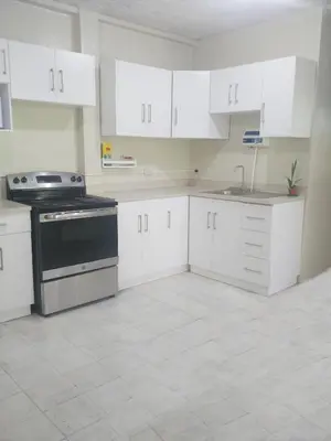 an empty kitchen with white cabinets and a stove at Queen Bed in San Salvador