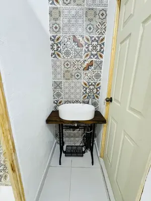 a bathroom with a sink and a tile wall at Urban Nest Hostel in Santa Ana