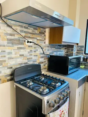 a stove top oven in a kitchen with a microwave at Conchita's, near Mall metrocentro, AC, SHW in Santa Ana