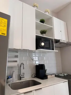 a kitchen with white cabinets and a sink and a microwave at Elegant Modern Tiny Home in San Miguel