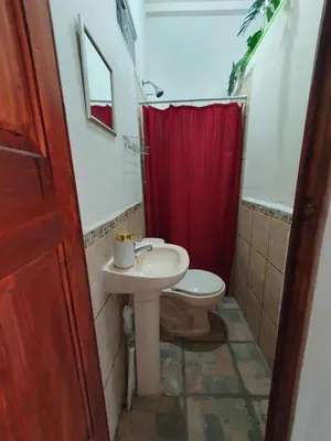 a bathroom with a sink and a toilet with a red shower curtain at Zacatecoluca House in Zacatecoluca