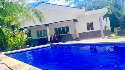 a house with a swimming pool in front of a house at Golden Sunset House in Acajutla